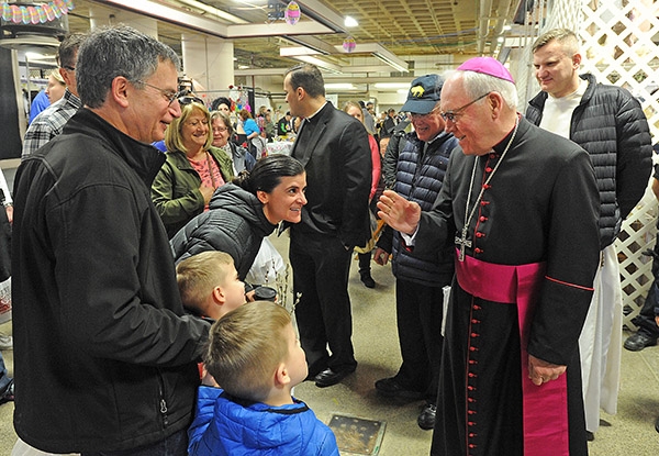 Bishop Richard J. Malone blesses a family during a visit to the Broadway Market on Saturday morning. (Dan Cappellazzo/Staff Photographer)